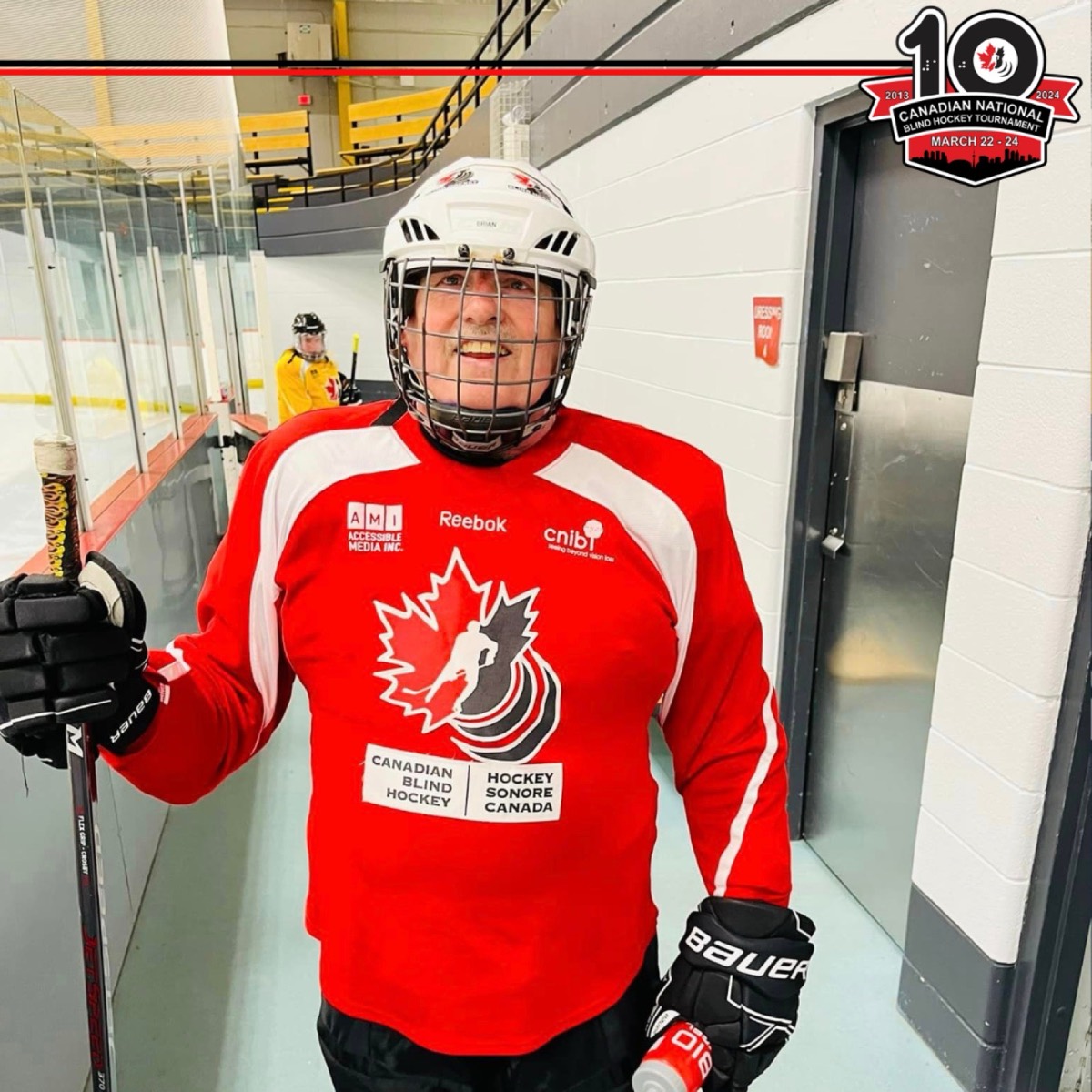 A smiling player in a red Canada Blind Hockey jersey at the rink, with the National Tournament's 10th-anniversary logo in the corner