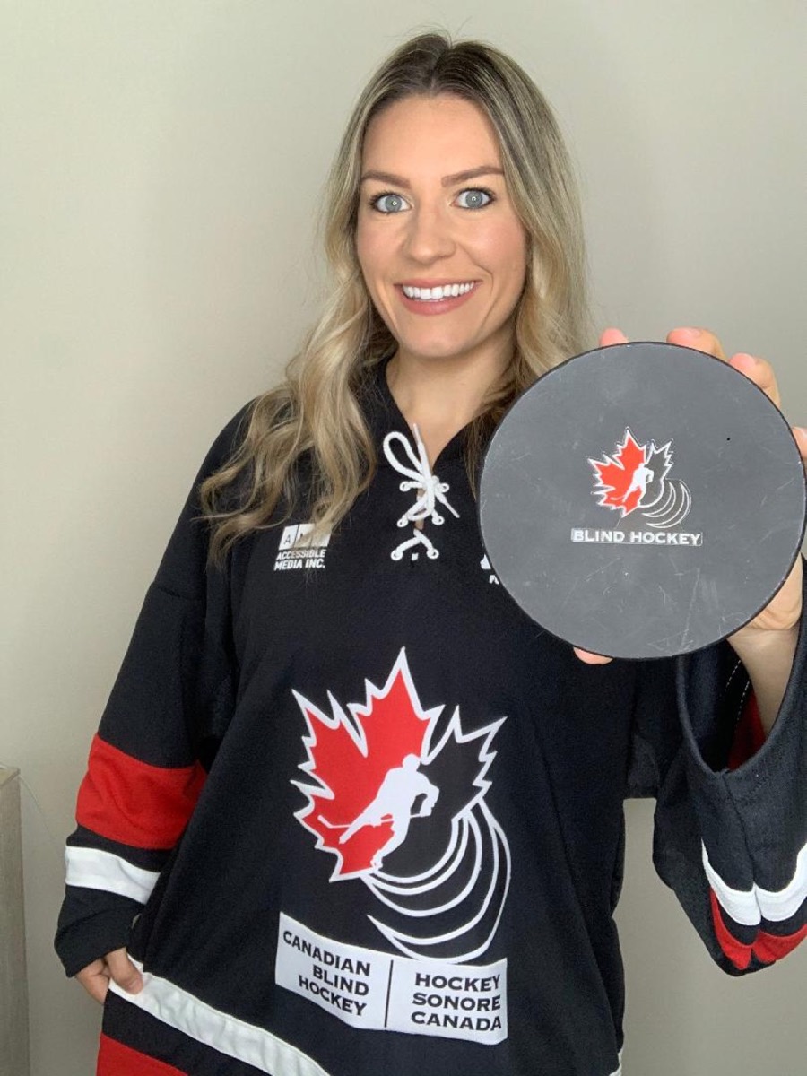 Canadian Blind Hockey ambassador Natalie Spooner in a Blind Hockey jersey, holding up the adapted puck