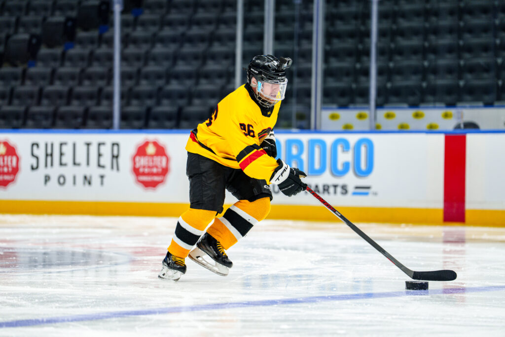 Corbin on ice in Minoru Arena chases a puck. He's wearing the new yellow Canucks Blind Hockey jersey.